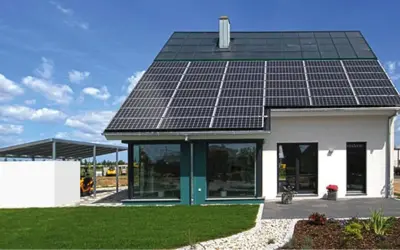 Ein modernes, energieautarkes Haus mit Solarmodulen auf dem Dach und einer Photovoltaik-Anlage auf dem Carport.