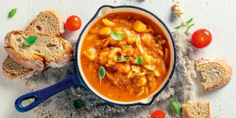 Herzhafte italienische Suppe mit Gemüse und Nudeln, serviert mit rustikalem Brot und frischen Tomaten. Ein Genuss für kalte Tage.
