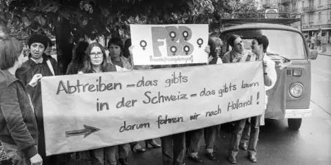 Frauen demonstrieren für das Recht auf Abtreibung. Die Botschaft "Abtreiben – das gibts in der Schweiz – das gibts kaum, darum fahren wir nach Holland!" zeigt eine frühe Welle des Feminismus.