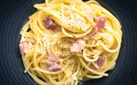 Spaghetti Carbonara mit herzhaftem Speck, cremig und mit frisch geriebenem Parmesan bestreut. Ein Klassiker, der immer schmeckt.