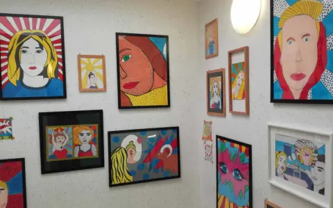 Bunte Pop-Art-Bilder, entstanden im Kunstunterricht, zieren die Wand. Porträts von Frauen im Comic-Stil, kräftige Farben und Linien.