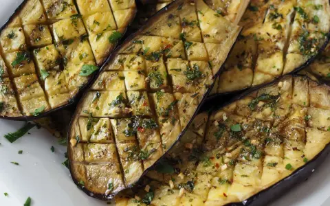 Gegrilltes Gericht mit Aubergine, gewürzt mit Kräutern und Knoblauch.