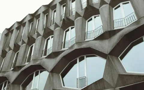 Fassade eines Gebäudes im Stil der brutalismus architektur mit geometrischen Betonformen und vielen Fenstern.