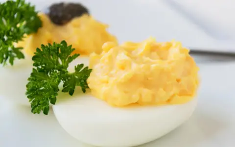 Zwei appetitliche russische Eier traditionell, gefüllt mit einer cremigen Eigelbmasse und garniert mit Petersilie.