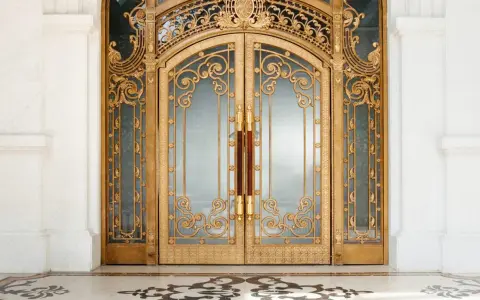 Prunkvolle goldene Doppeltür im **Art déco Baustil** mit filigranen Verzierungen und Marmorboden.