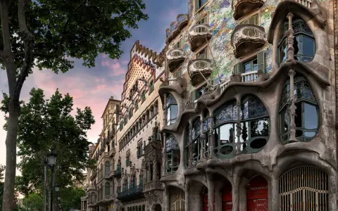 Casa Batlló in Barcelona, ein Meisterwerk des Art Nouveau, mit seinen organischen Formen und bunten Mosaiken, unter einem rosafarbenen Himmel.