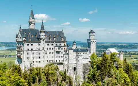 Märchenschloss Neuschwanstein, ein Meisterwerk romantischer Architektur, thront auf einem Felsen über einer malerischen Landschaft.