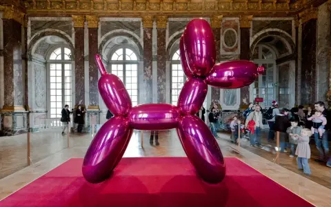 Jeff Coons' glänzender Ballonhund in Pink, ausgestellt in einem prunkvollen Saal mit Besuchern.