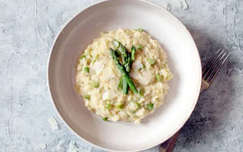 Cremiges Spargel-Erbsen-Risotto, garniert mit frischem Spargel und Parmesan. Ein Beweis für die besten Risotto Rezepte.