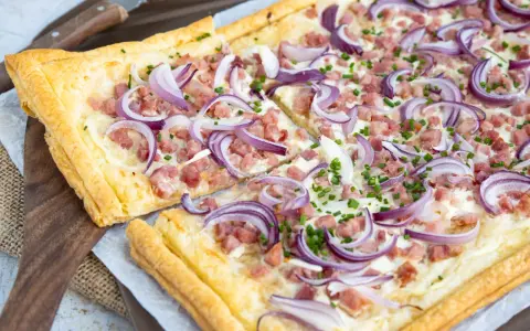 Flammkuchen varianten: knuspriger Teig mit Speck, Zwiebeln und Schnittlauch belegt.