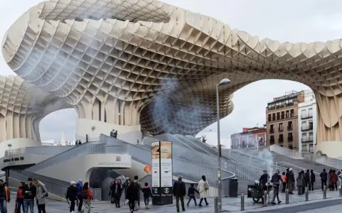 Ein Meisterwerk des Dekonstruktivismus: die Metropol Parasol in Sevilla. Menschen schlendern unter der organisch geformten Holzkonstruktion hindurch.