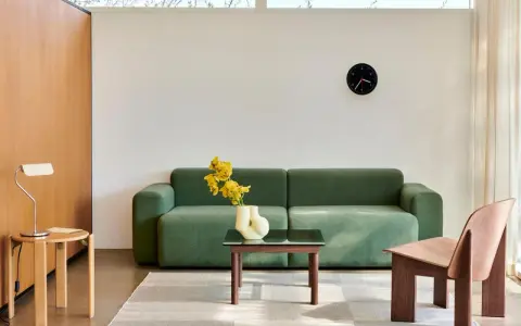 Grünes Sofa, Holztisch, Vase mit gelben Blumen und ein Stuhl im skandinavischen Einrichtungsstil.