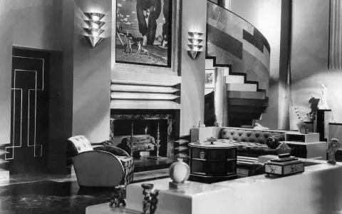 Elegantes Wohnzimmer im **art deco stil** mit geschwungener Treppe, Kamin und stilvollen Möbeln.