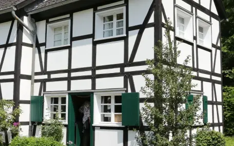 Ein liebevoll saniertes Fachwerkhaus mit grünen Fensterläden und üppiger Bepflanzung.