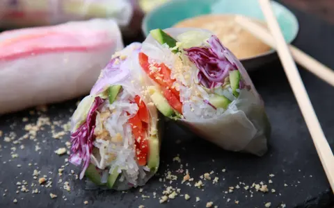 Frische, bunte Sommerrollen mit Reisnudeln, Gurke, Tomate und Rotkohl, bestreut mit Erdnüssen. Perfekt für einen leichten Snack.