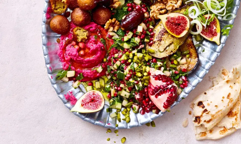 Bunte Mezze-Platte mit Hummus, Falafel, Granatapfel, Feigen und Fladenbrot. Perfekt für ein köstliches Abendessen.